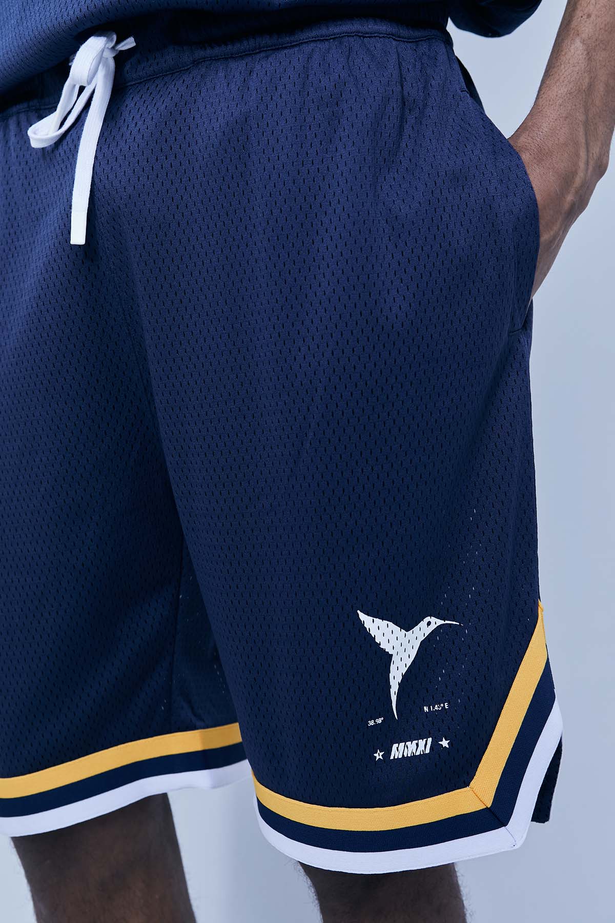 Wide Bermuda shorts made of mesh fabric with an open and elastic structure. Adjustable elastic waist inside. Laces with rubberized ends. Printing detail on the front. Side hip pockets.