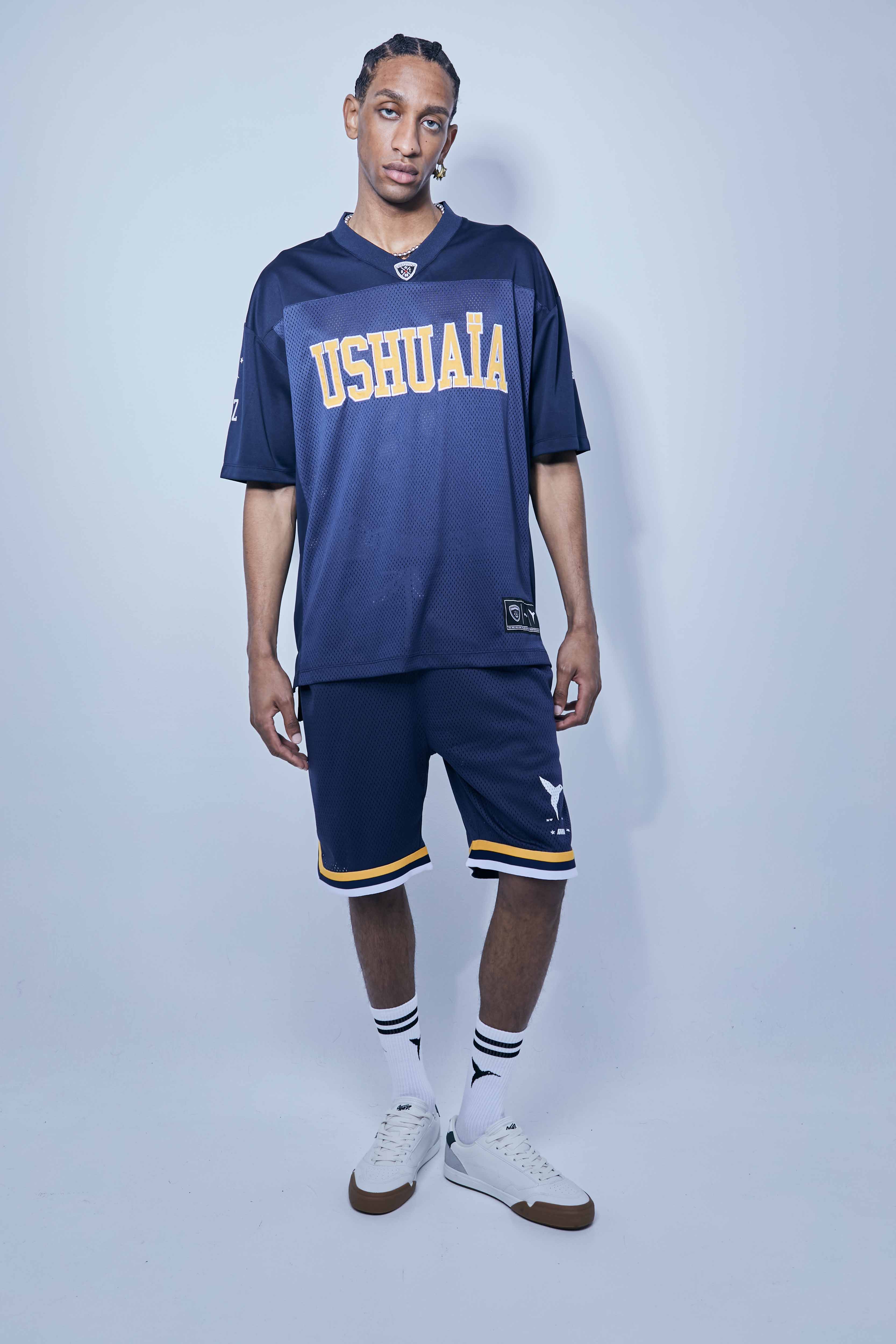 Wide Bermuda shorts made of mesh fabric with an open and elastic structure. Adjustable elastic waist inside. Laces with rubberized ends. Printing detail on the front. Side hip pockets.