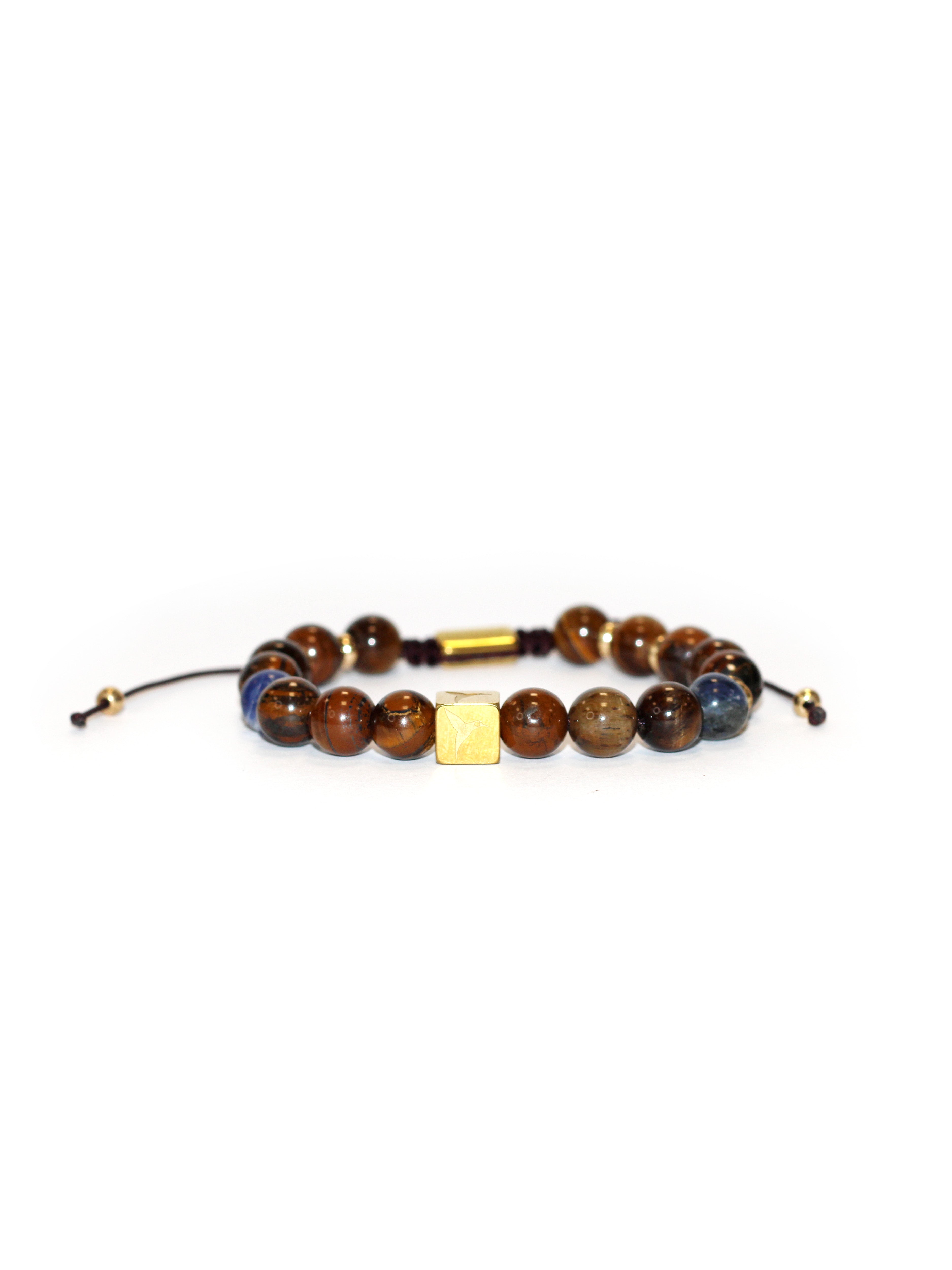 Adjustable bracelet with textile cord. Round beads in brown, blue, and wood-effect tones. Gold-finish central metal piece with engraved logo. Unisex design.
COMPOSITION:
resin, natural stone, metal alloy, textile cord.