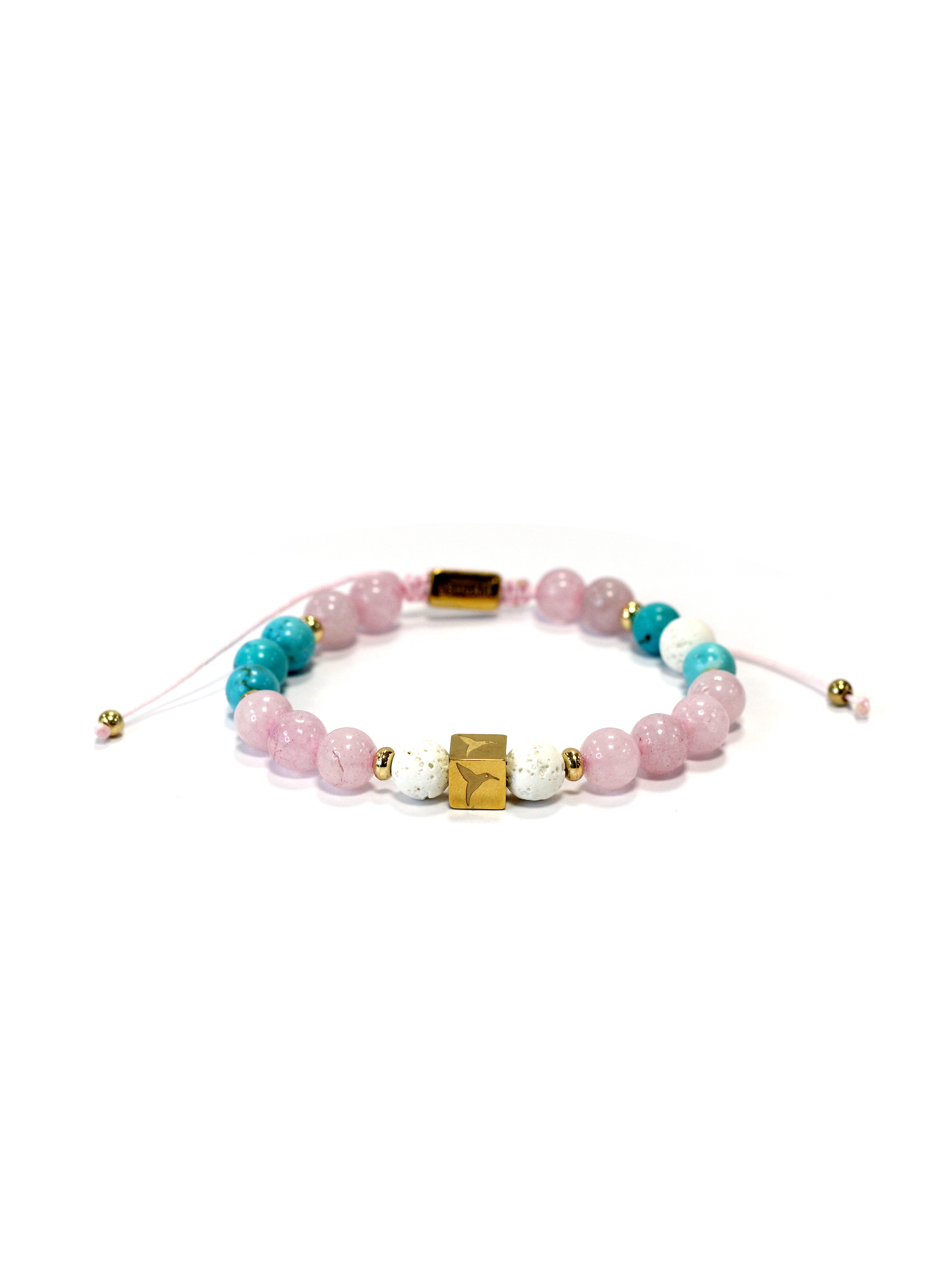 Adjustable bracelet with textile cord. Round beads in pink, turquoise, and white tones, with gold metallic details. Central cube-shaped metal piece with engraved logo. Unisex design.
COMPOSITION:
natural stone, resin, metal alloy, textile cord.