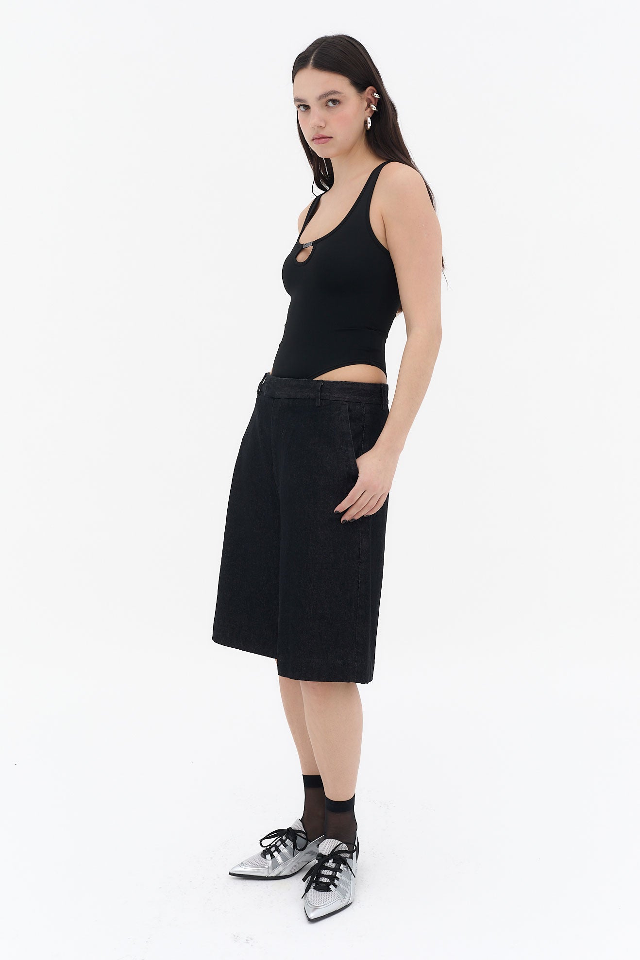 Body negro con tirantes anchos y escote redondo, con abertura frontal y pieza metálica central con logotipo, confeccionado en tejido elástico de nylon y spandex.