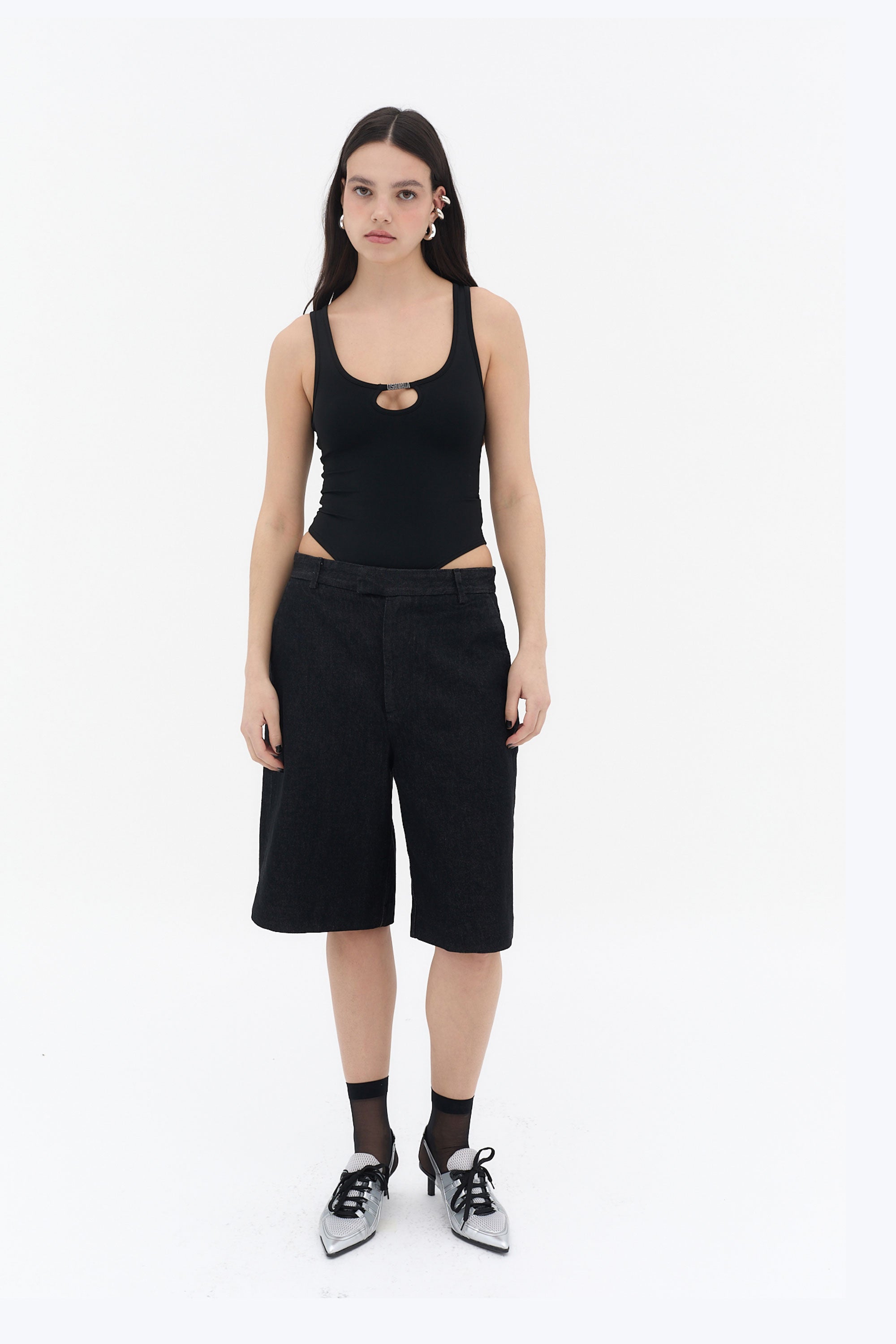Body negro con tirantes anchos y escote redondo, con abertura frontal y pieza metálica central con logotipo, confeccionado en tejido elástico de nylon y spandex.