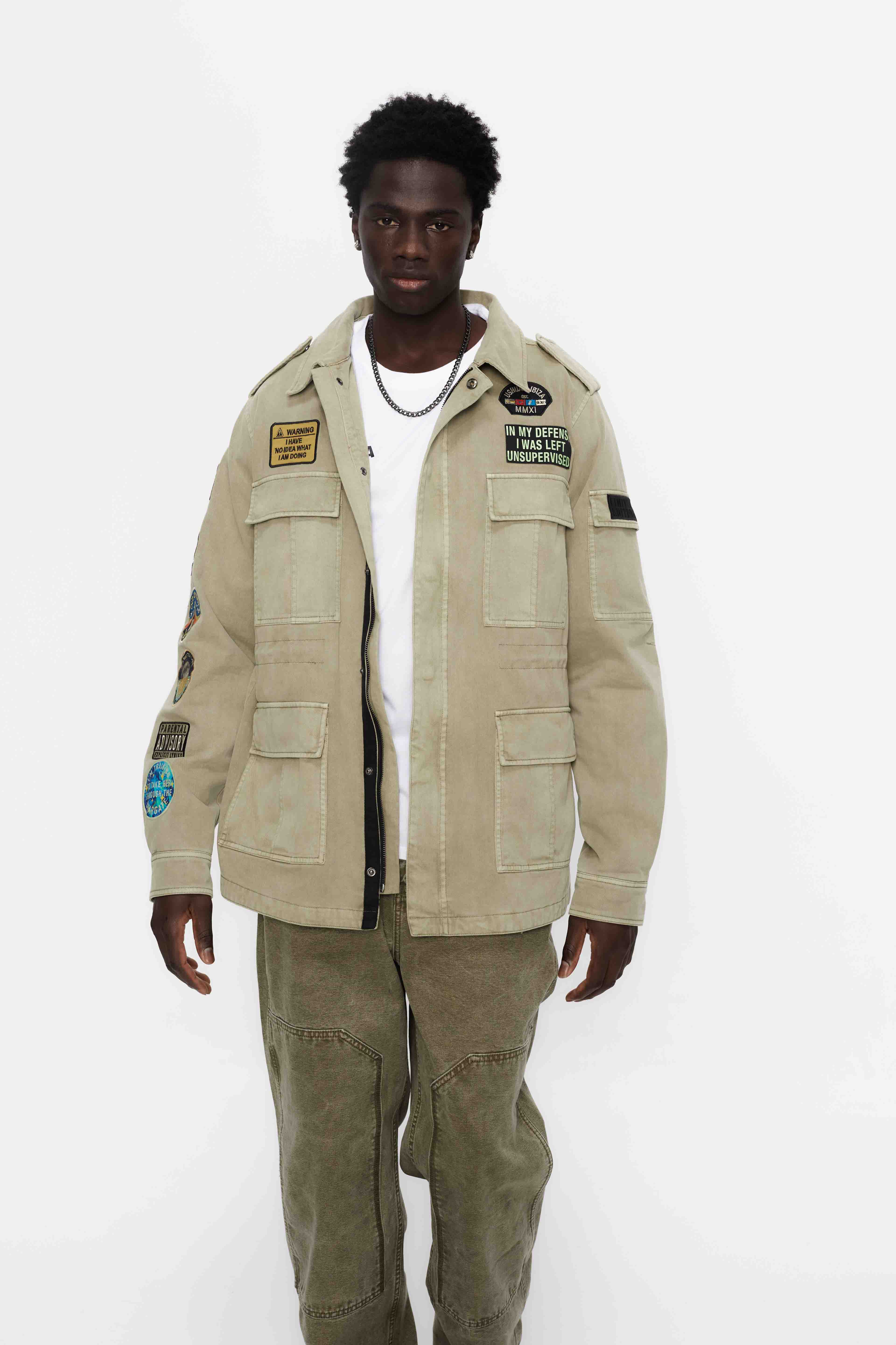 Washed twill military jacket with shirt collar and long sleeves with adjustable cuff with button. Central zip closure with adjustable drawstring at the waist. Patch pockets and flap on the front and sleeve. Combination of patches and embroidered application on front and back. Custom label detail on the back.
