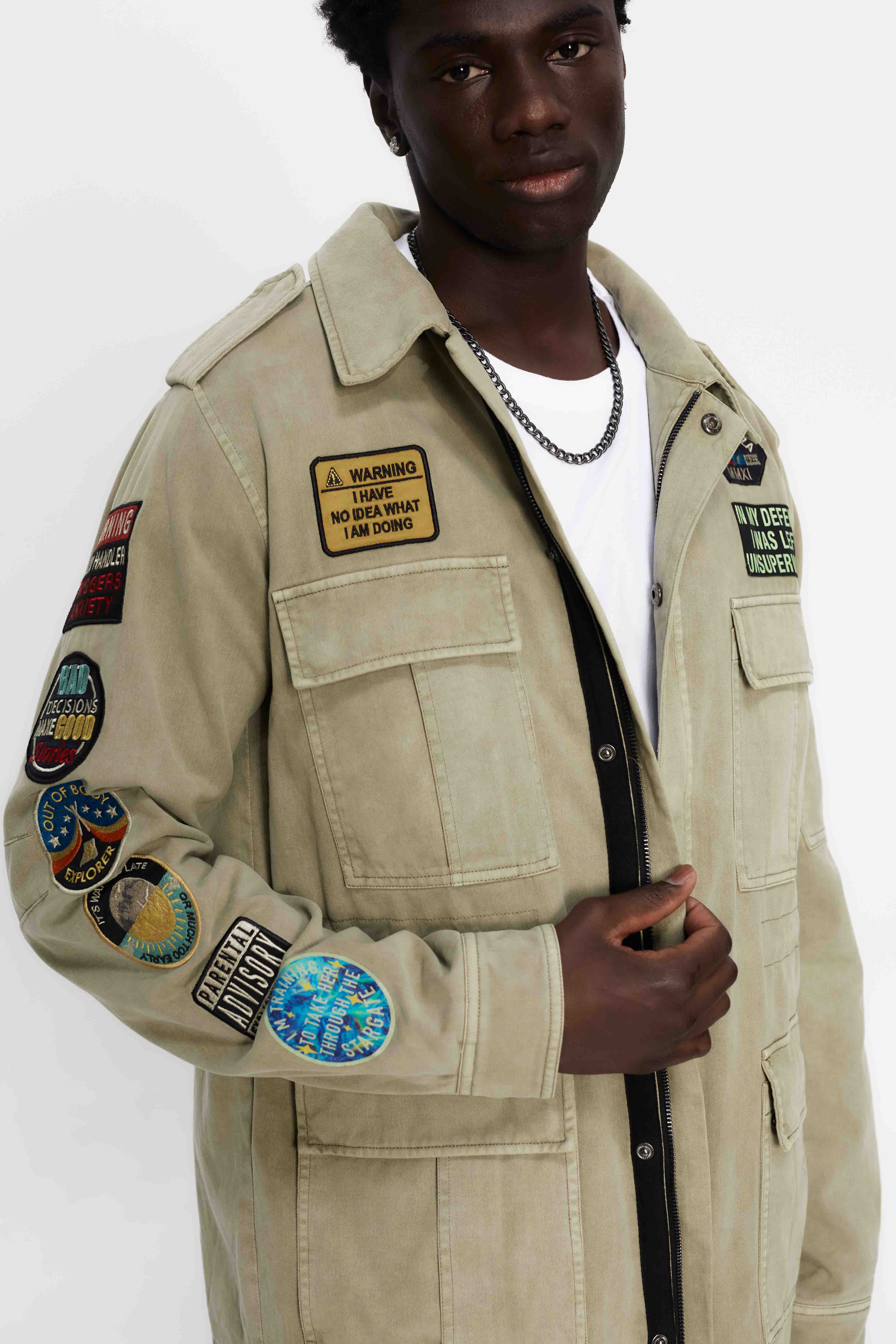Washed twill military jacket with shirt collar and long sleeves with adjustable cuff with button. Central zip closure with adjustable drawstring at the waist. Patch pockets and flap on the front and sleeve. Combination of patches and embroidered application on front and back. Custom label detail on the back.