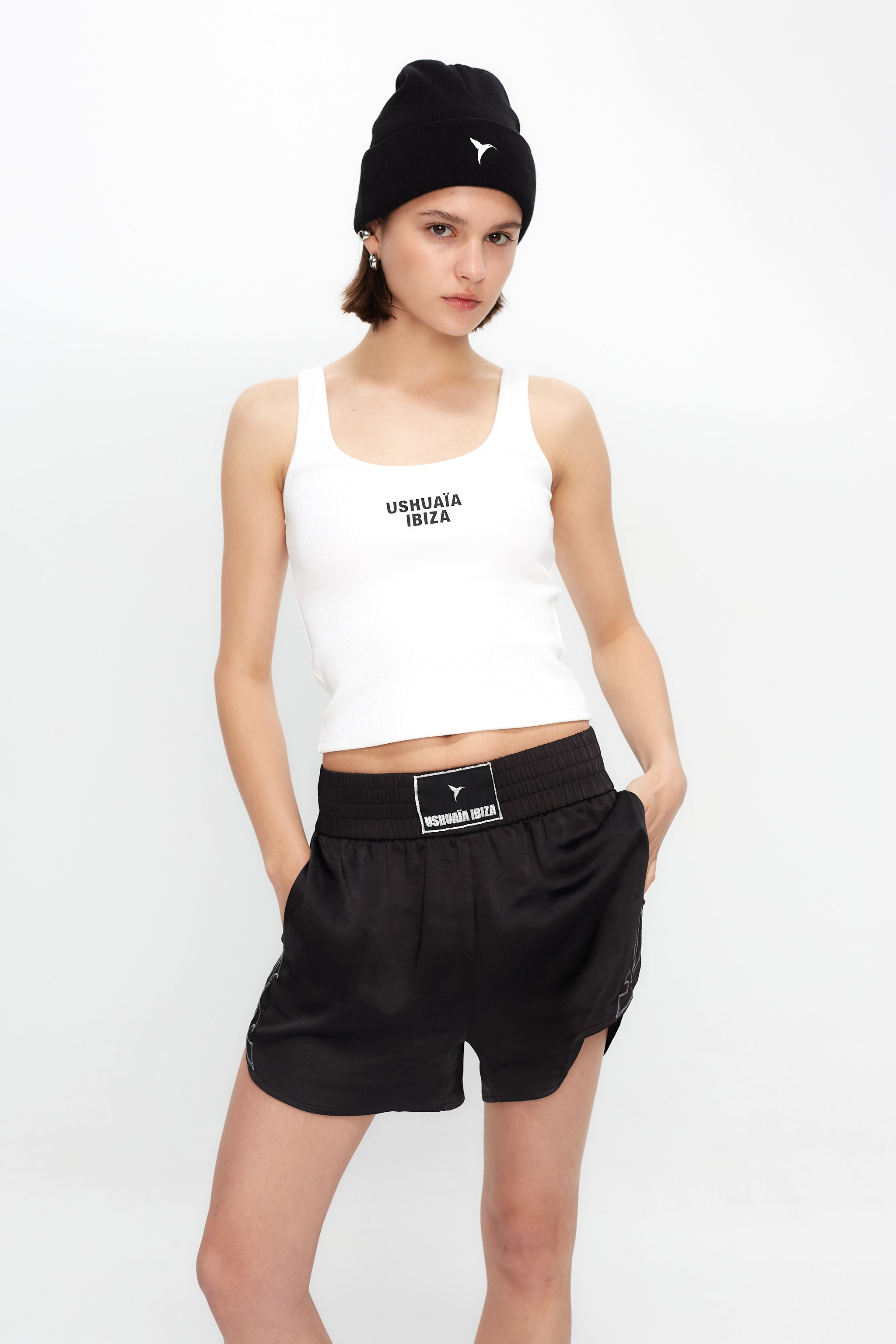 Satin-style black shorts with elastic waist and metallic finish. Perfect for bold summer looks in Ibiza. Shop now!