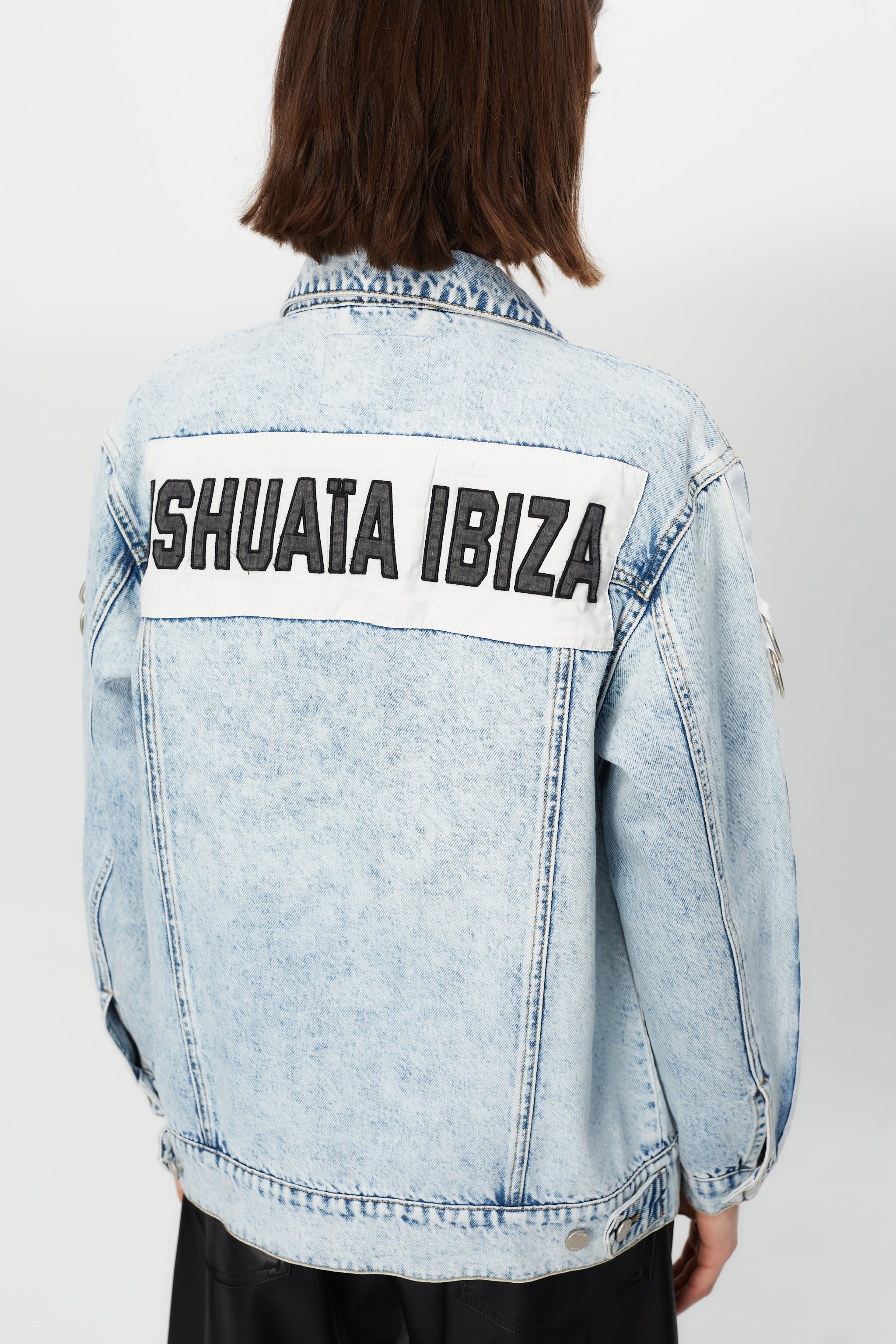 Denim jacket with a back panel featuring an appliqué with applied text and embroidery. Side sleeve panel embroidered with silver eyelet finish.