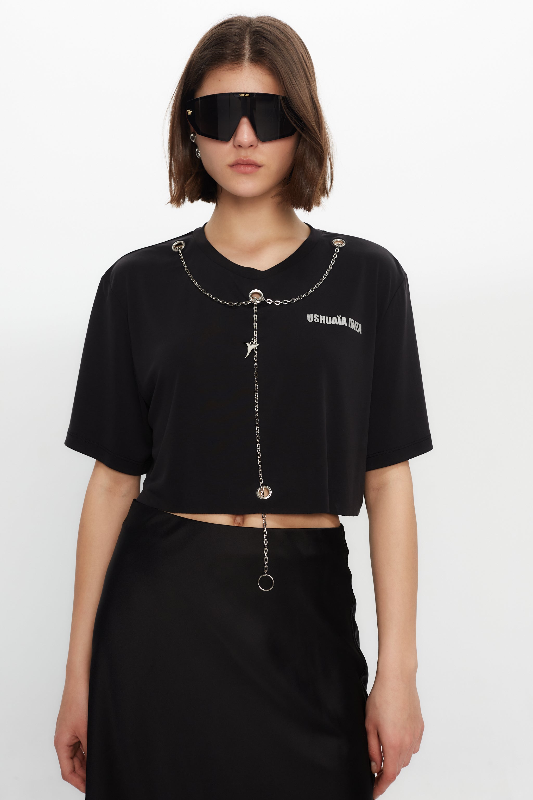 Black cropped T-shirt with metallic finish, bold front print & chain details. Perfect for edgy Ibiza vibes. Shop the trend now!