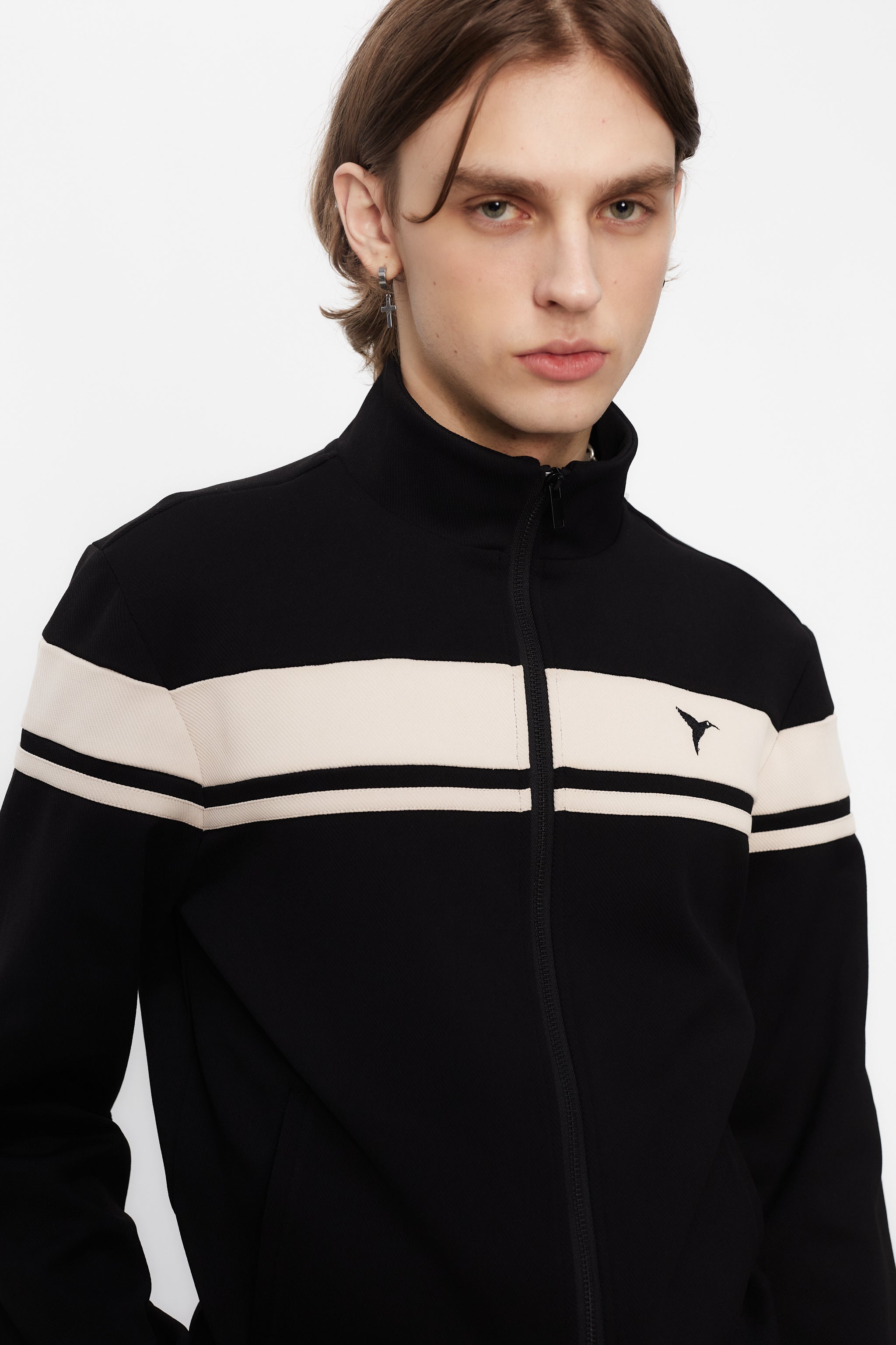 Sports jacket with mandarin collar and central zipper. Contrast combined embroidery detail on the back. Front welt pockets. Ribbed finishes.