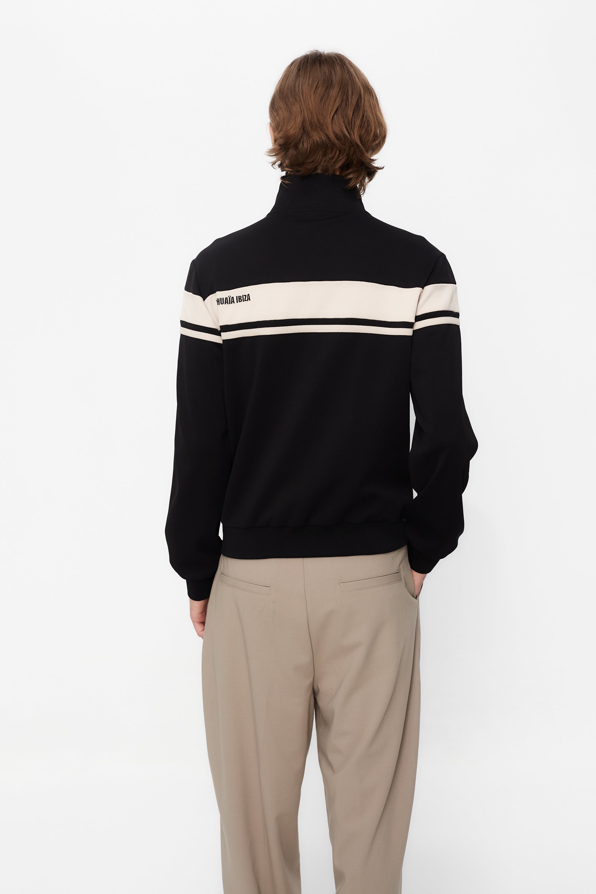 Sports jacket with mandarin collar and central zipper. Contrast combined embroidery detail on the back. Front welt pockets. Ribbed finishes.