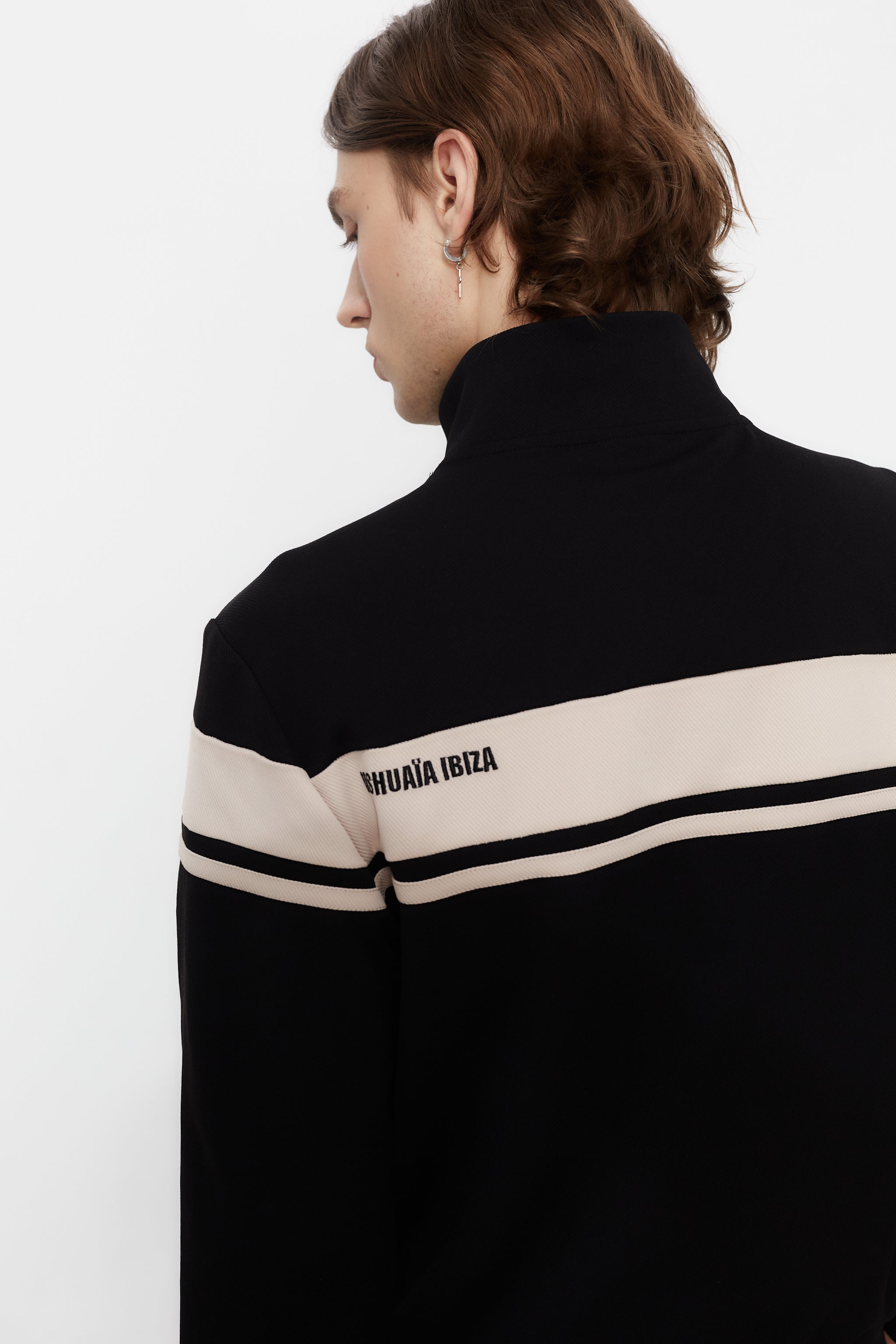 Sports jacket with mandarin collar and central zipper. Contrast combined embroidery detail on the back. Front welt pockets. Ribbed finishes.