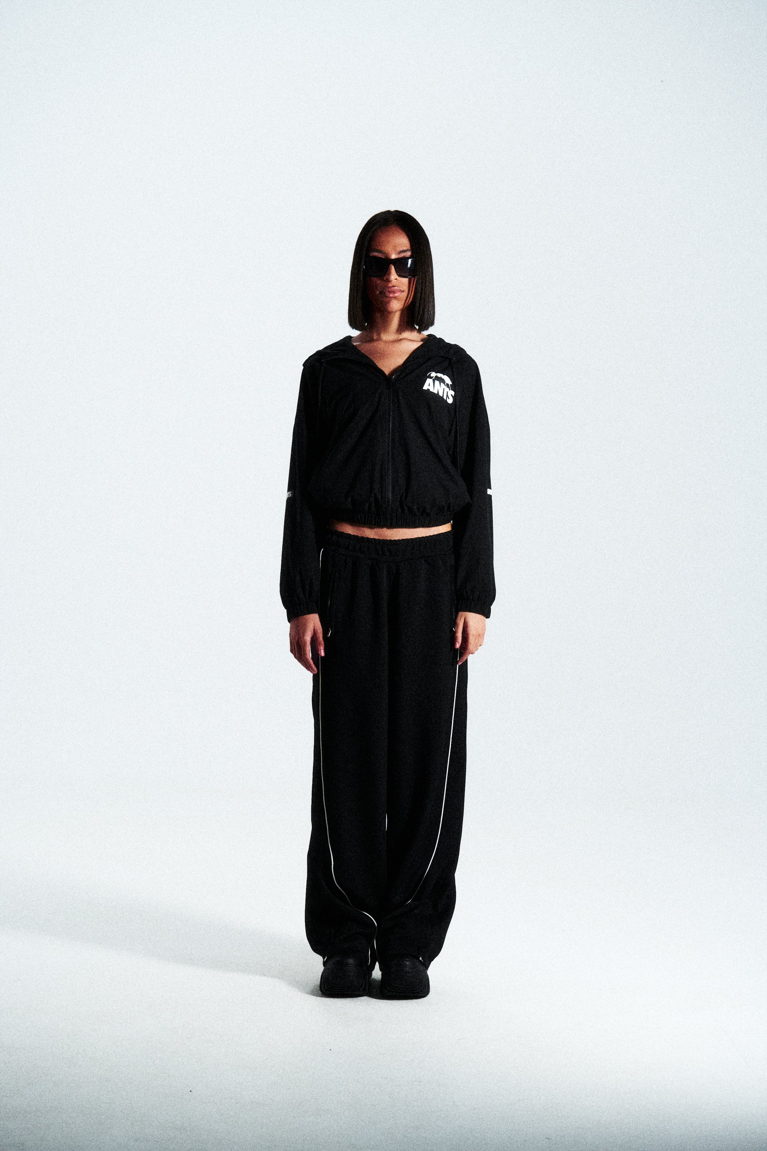 Lightweight technical nylon jacket with a matte finish. Features a white screen-printed ANTS logo on the left pocket and hood for contrast.