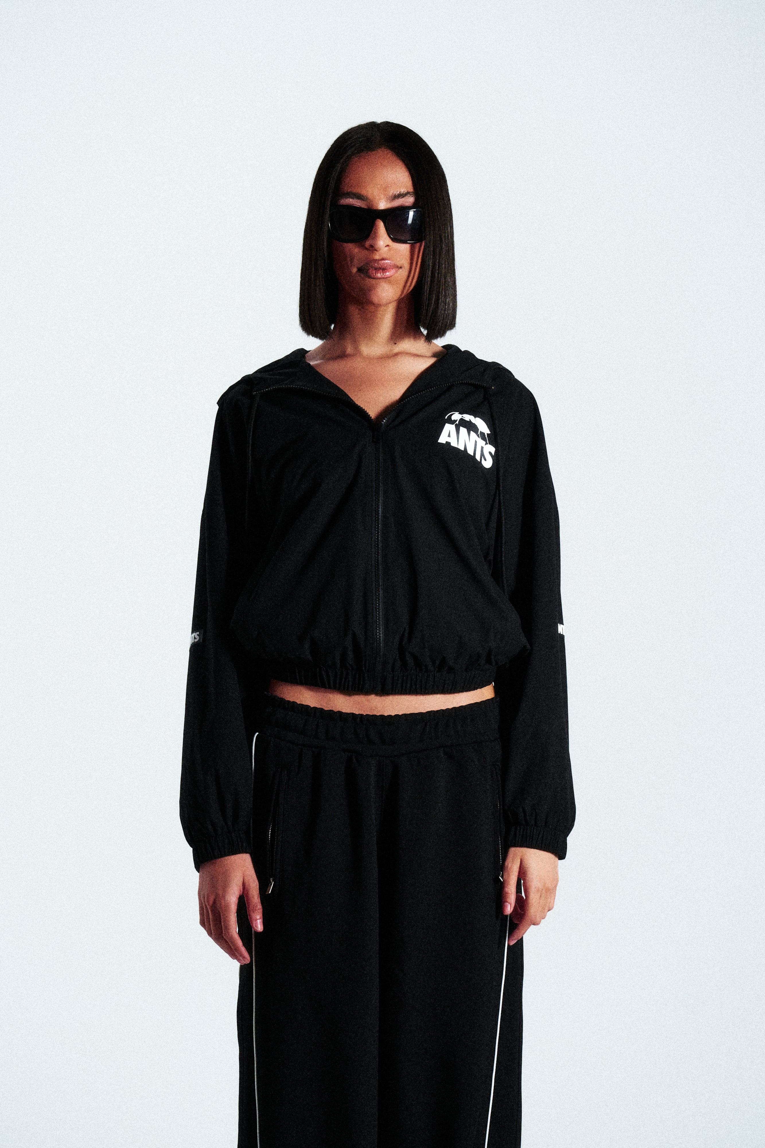 Lightweight technical nylon jacket with a matte finish. Features a white screen-printed ANTS logo on the left pocket and hood for contrast.