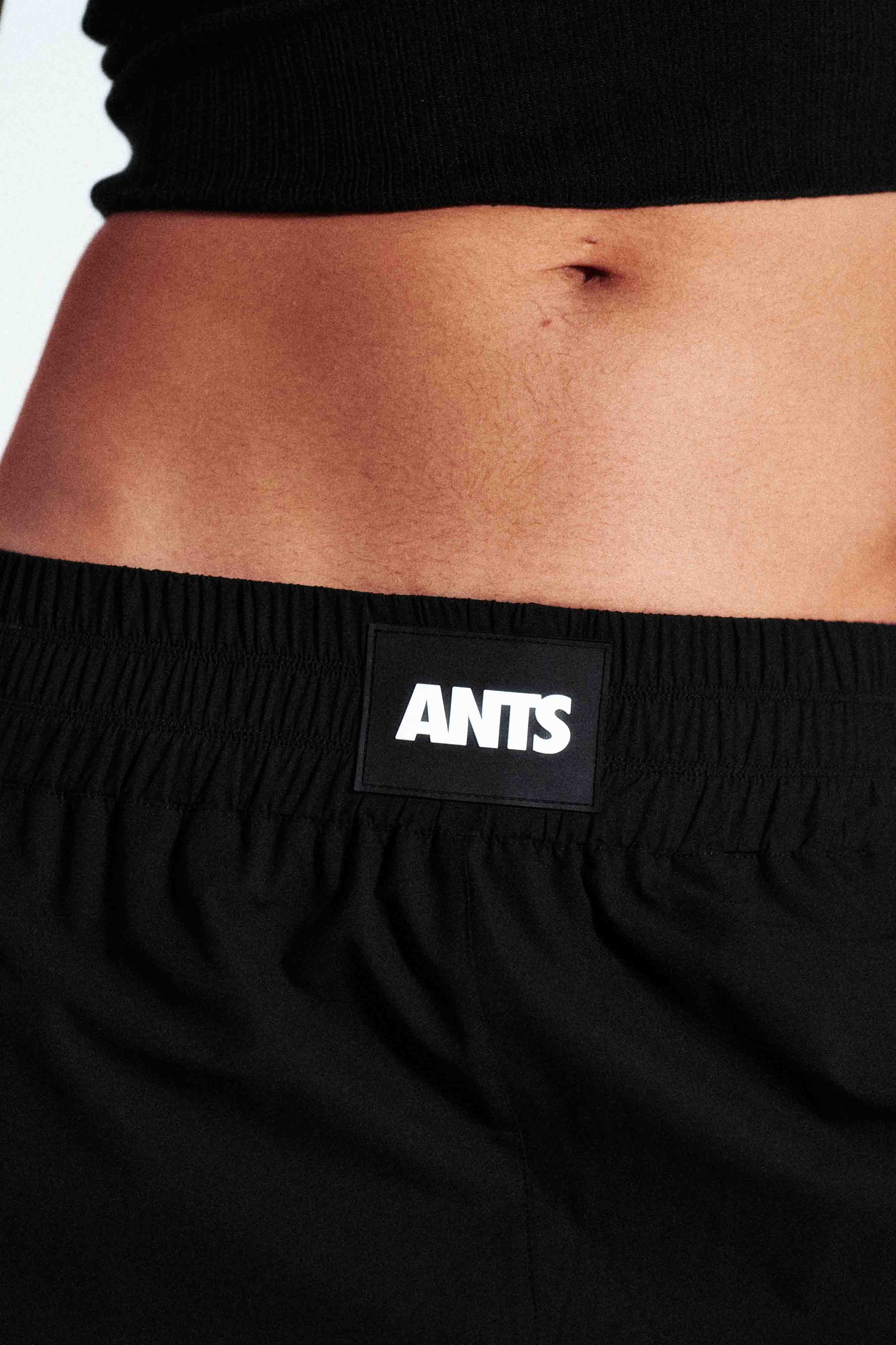High-waisted ANTS performance shorts with elastic waistband and bold hem logo. Premium stretch fabric.