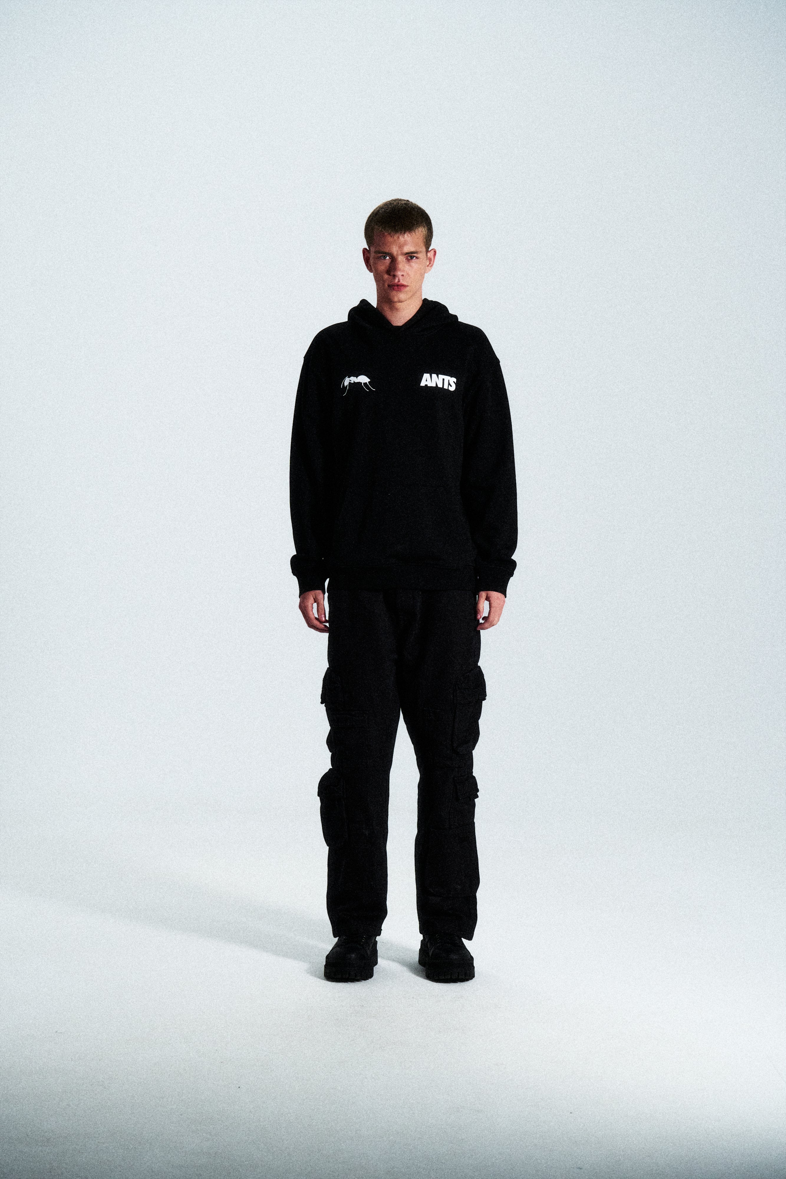 The Built Stronger Hoodie is crafted from French Terry Cotton. The black hoodie is emblazoned with a white ANTS logo on the front and features artwork on the back. A unique piece of merchandise and a versatile addition to any outfit.