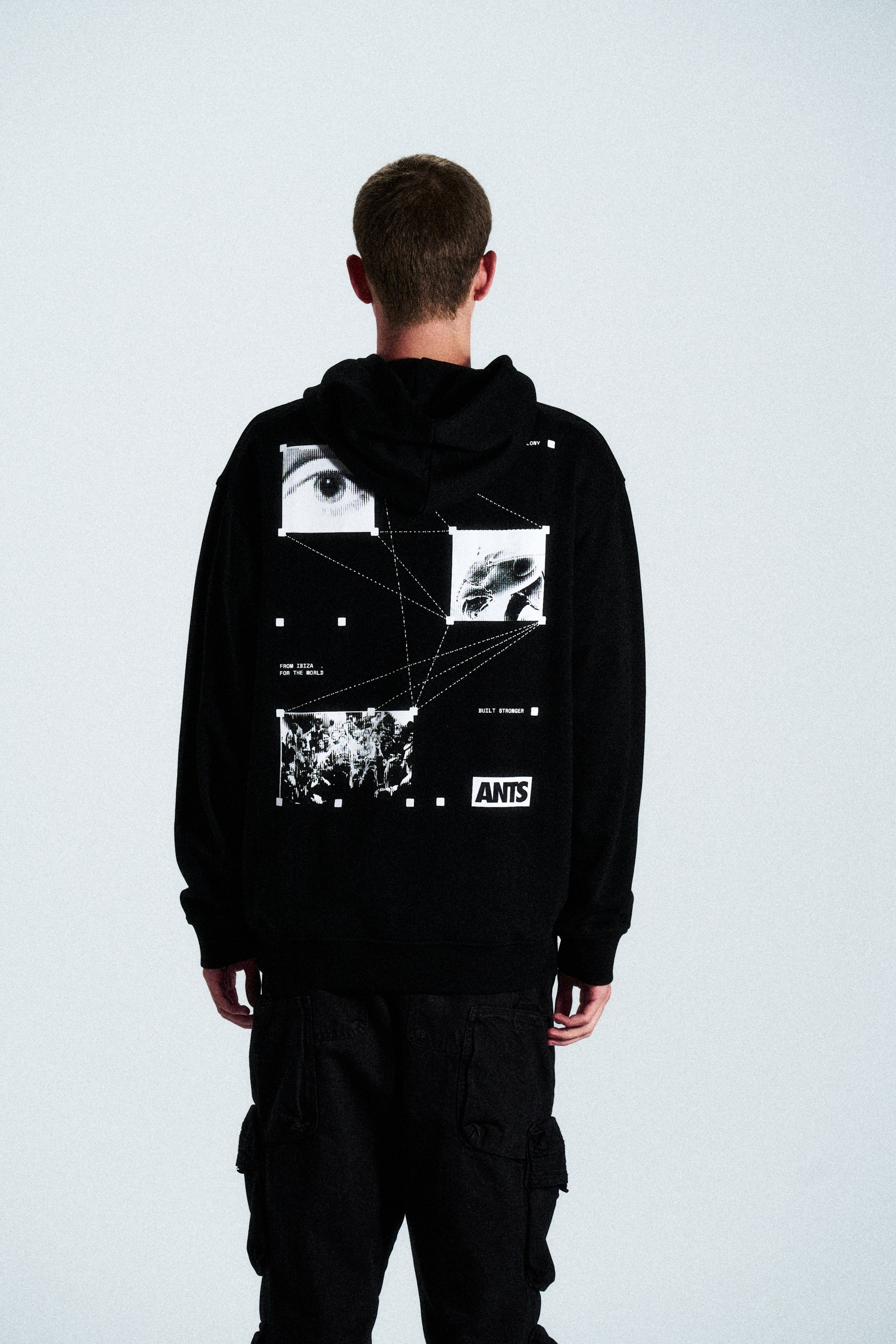 The Built Stronger Hoodie is crafted from French Terry Cotton. The black hoodie is emblazoned with a white ANTS logo on the front and features artwork on the back. A unique piece of merchandise and a versatile addition to any outfit.