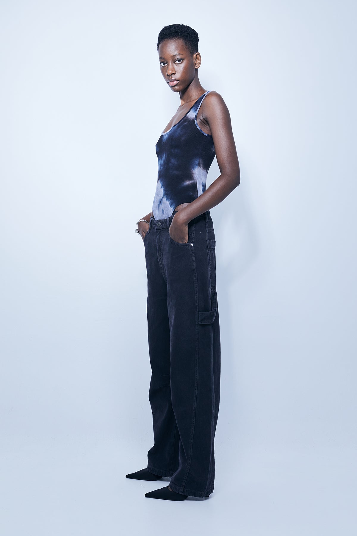 Washed rib bodysuit with tie-dye effect. Round neckline and straps. Embroidery detail on the front. Bottom closure with snap buttons.