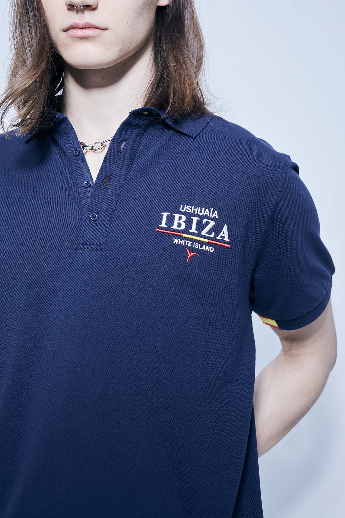 Polo made of cotton fabric with a mercerized finish. Lapel collar with front button closure and short sleeves. Embroidered application detail on the front