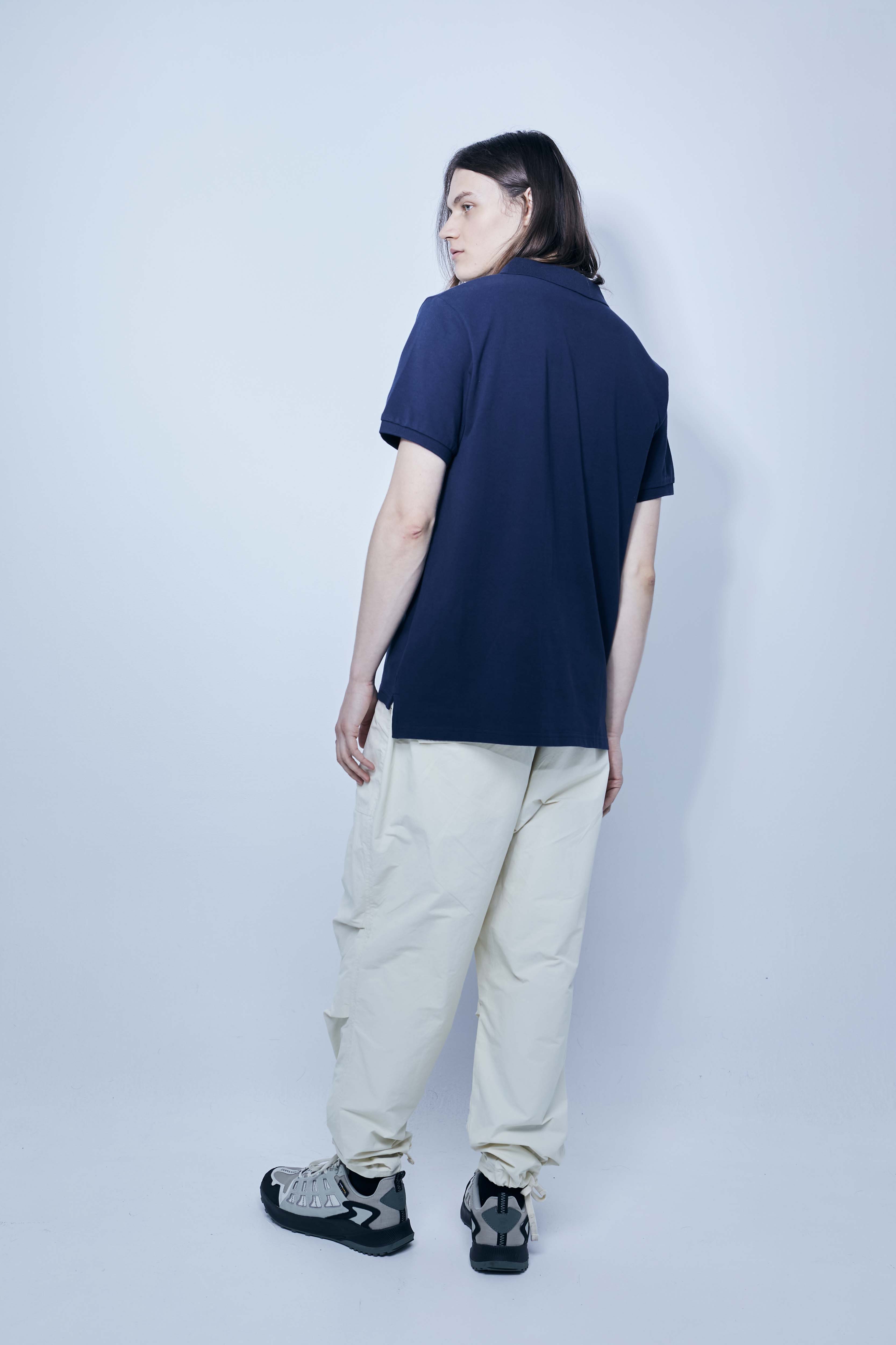 Polo made of cotton fabric with a mercerized finish. Lapel collar with front button closure and short sleeves. Embroidered application detail on the front