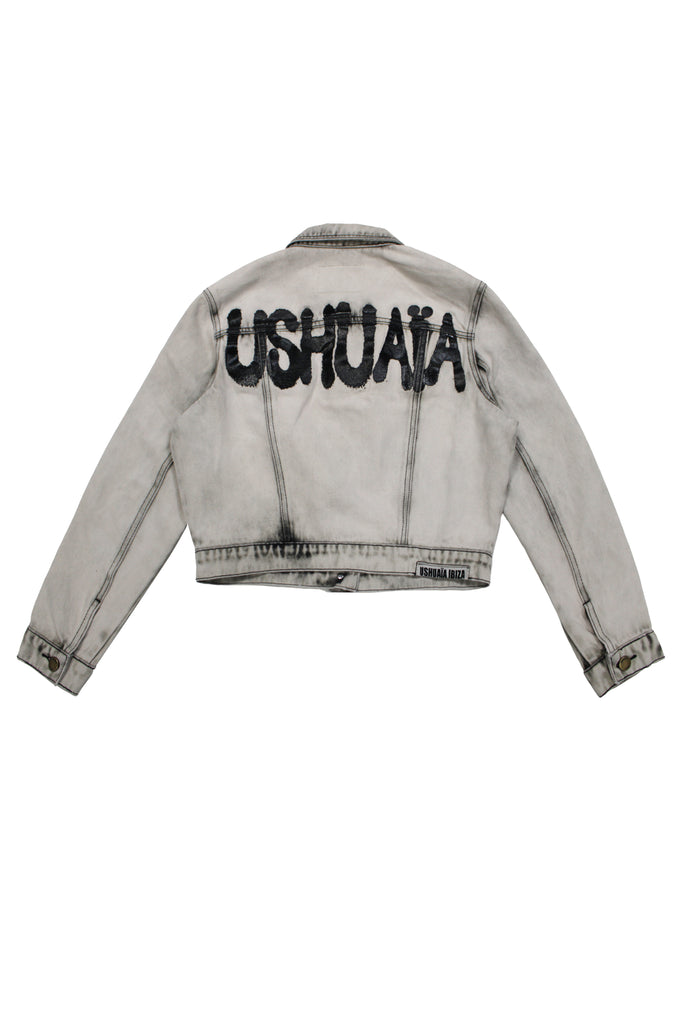 Cropped denim jacket with lapel collar and long sleeves, washed with a fade-out effect. Front closure with metal buttons. Features embroidery detail on the front and contrast combined print on the back. 