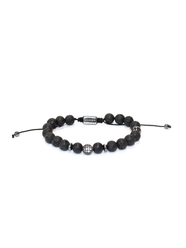 Adjustable bracelet with waxed cord. Black volcanic stone and metal beads. Central detail with inlays and engraved Ushuaïa metal tag. One size, unisex design.
COMPOSITION:  
volcanic stone, metal alloy, textile cord.