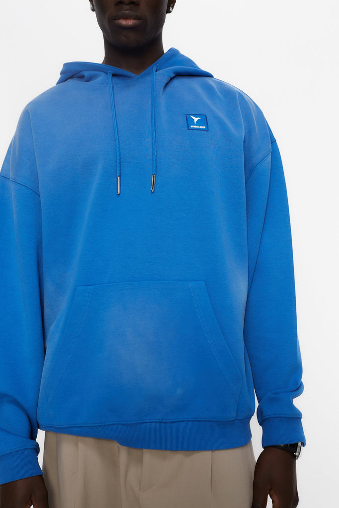 Oversized sweatshirt with adjustable hood with drawstring and long sleeves washed with enzymatic effect. Contrast combined patch detail on the front and print on the back. Kangaroo pocket on the front. Ribbed finishes.  
