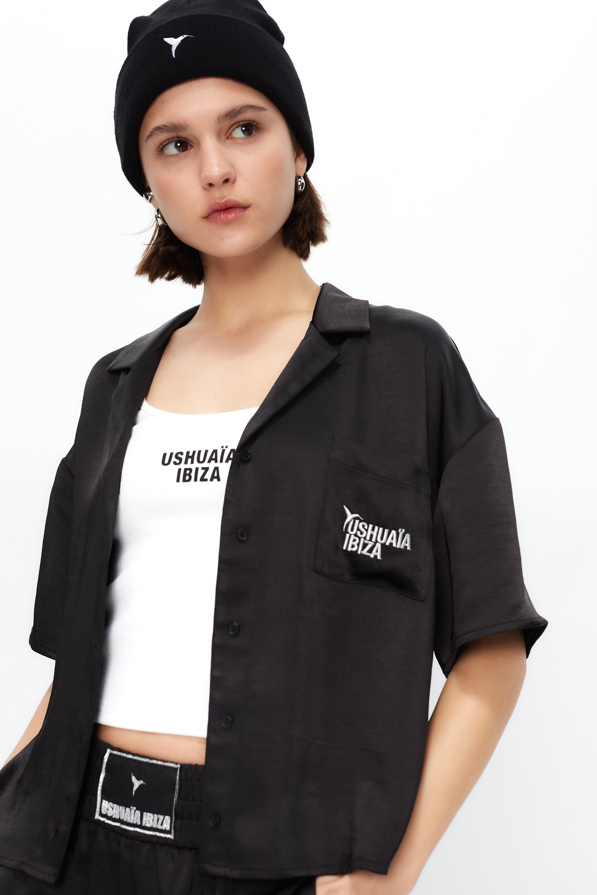 Cropped shirt with lapel collar made of satin fabric. Features an embroidery detail with lurex thread on the front pocket.