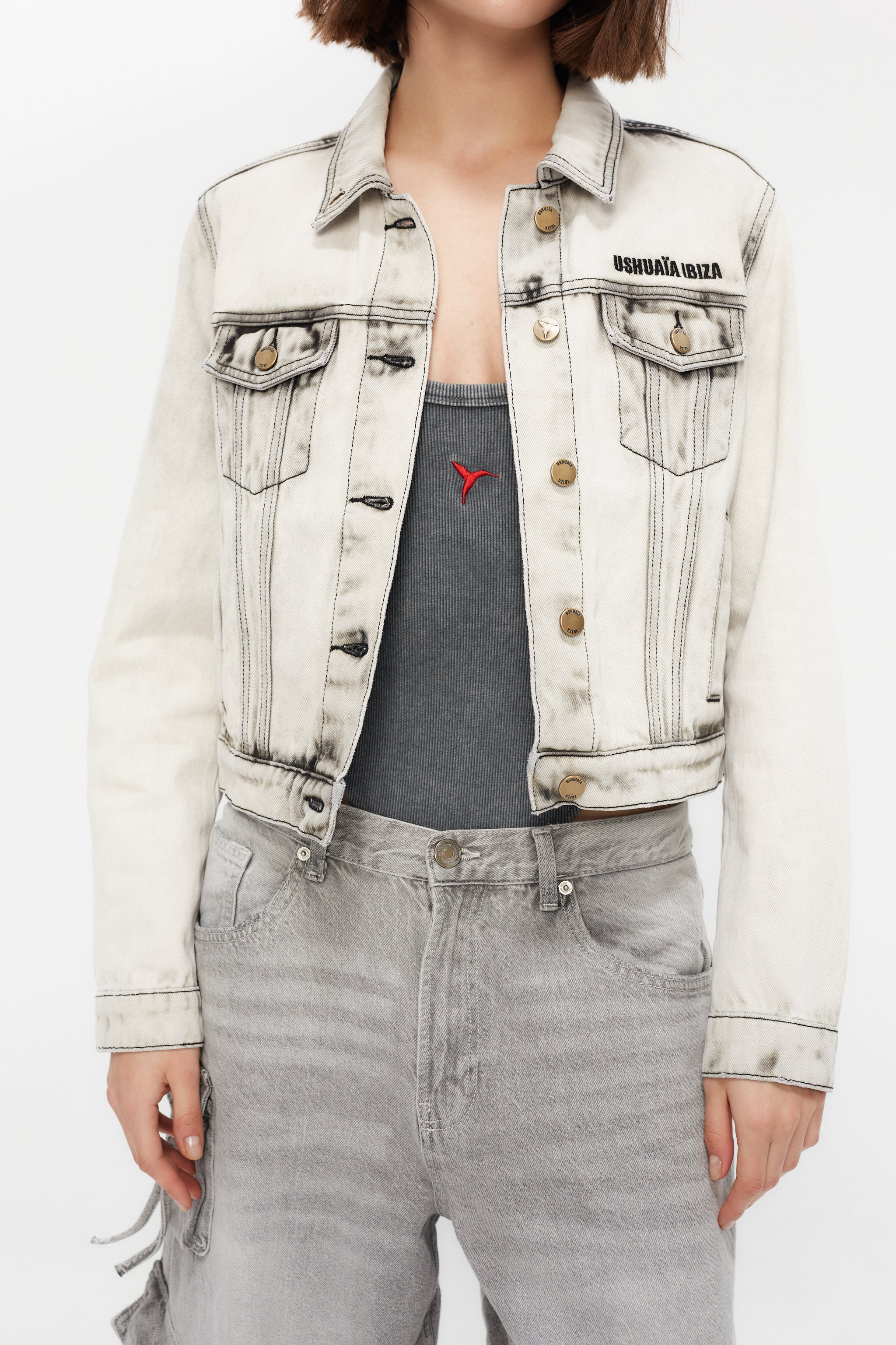 Cropped denim jacket with lapel collar and long sleeves, washed with a fade-out effect. Front closure with metal buttons. Features embroidery detail on the front and contrast combined print on the back. 