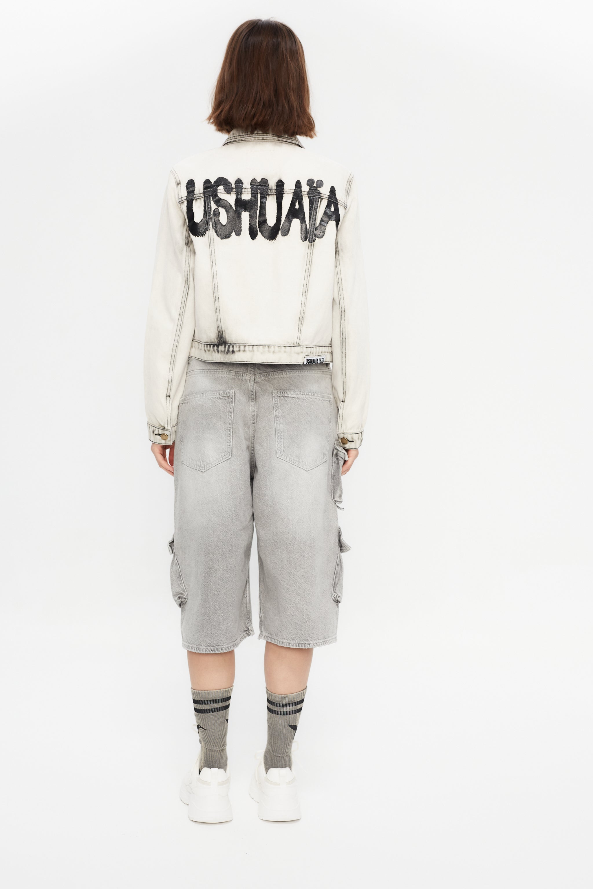 Cropped denim jacket with lapel collar and long sleeves, washed with a fade-out effect. Front closure with metal buttons. Features embroidery detail on the front and contrast combined print on the back. 