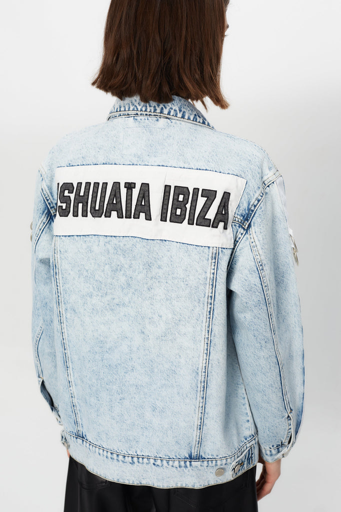 Denim jacket with a back panel featuring an appliqué with applied text and embroidery. Side sleeve panel embroidered with silver eyelet finish.