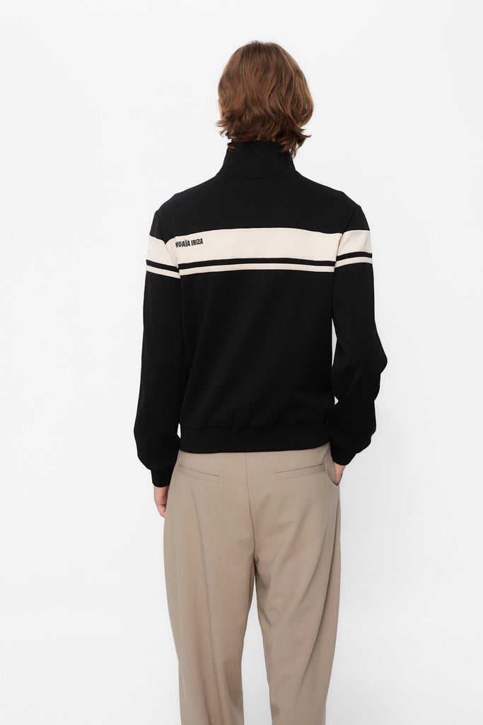 Sports jacket with mandarin collar and central zipper. Contrast combined embroidery detail on the back. Front welt pockets. Ribbed finishes.